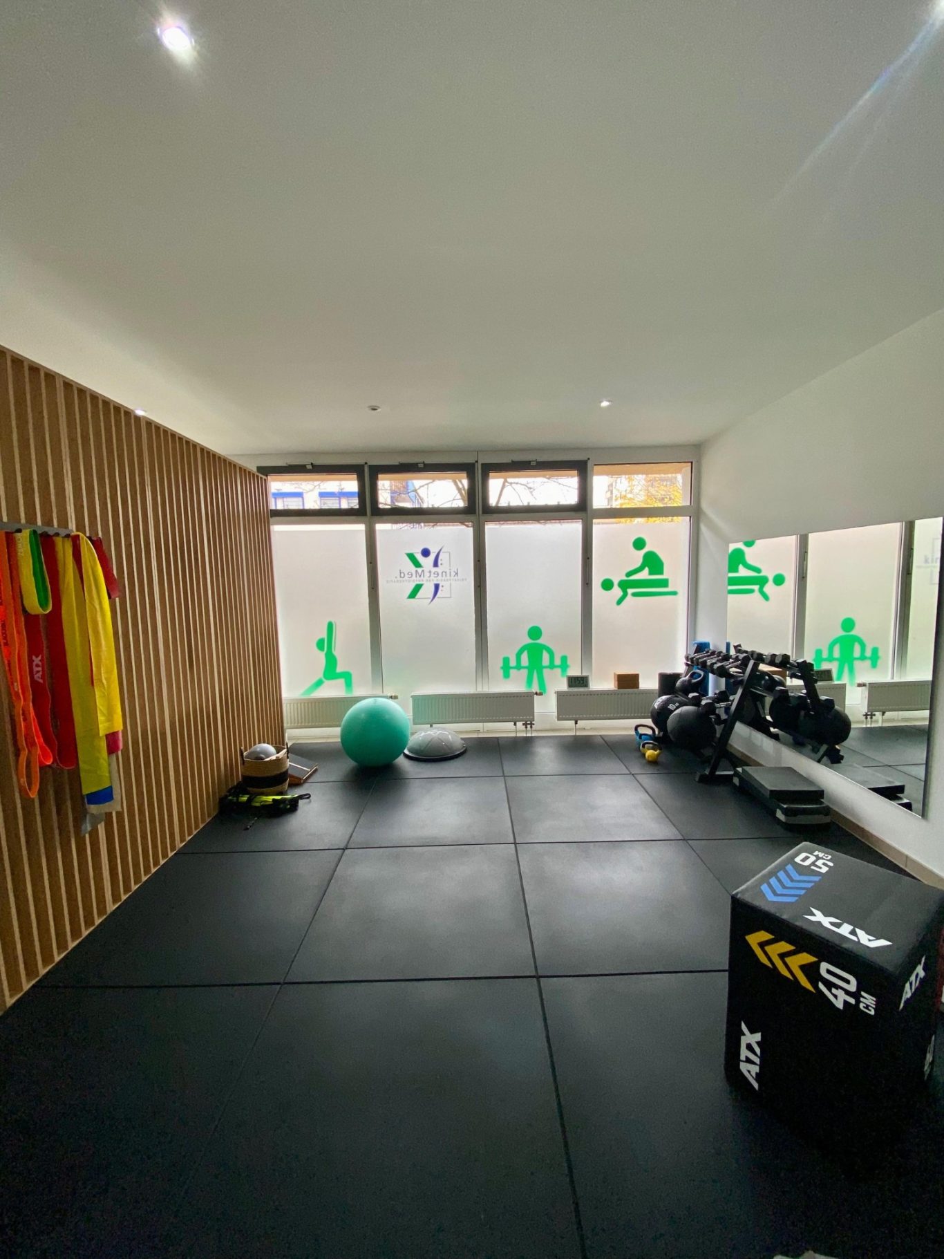 Moderner Trainingsraum der Physiotherapie kinetMed München mit Hanteln, Gymnastikbällen und funktionellem Equipment für Reha-Training.