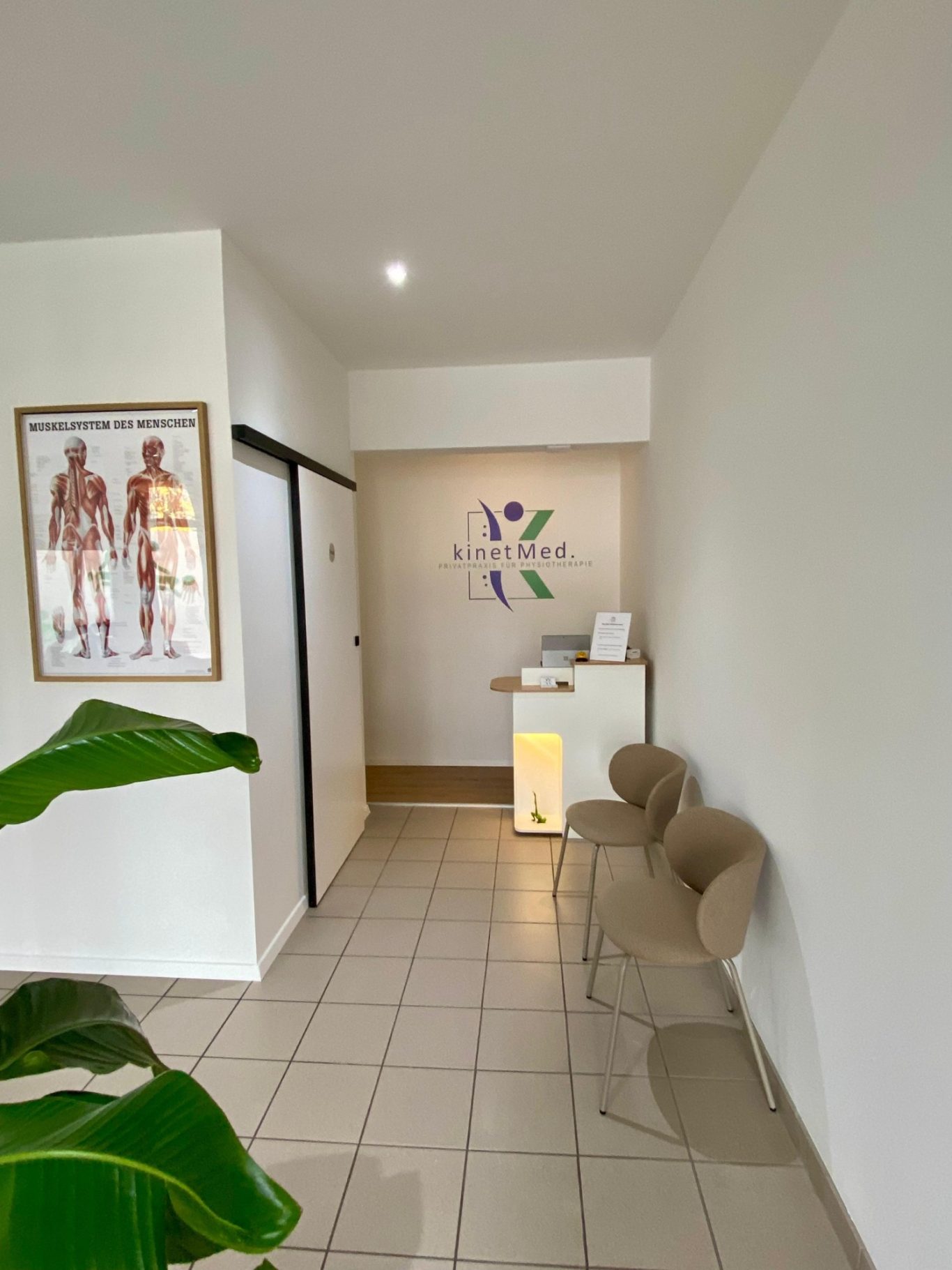 Einladender Empfangsbereich mit Rezeption und dem dahinter befindlichen Logo der Physiotherapie Praxis kinetMed.